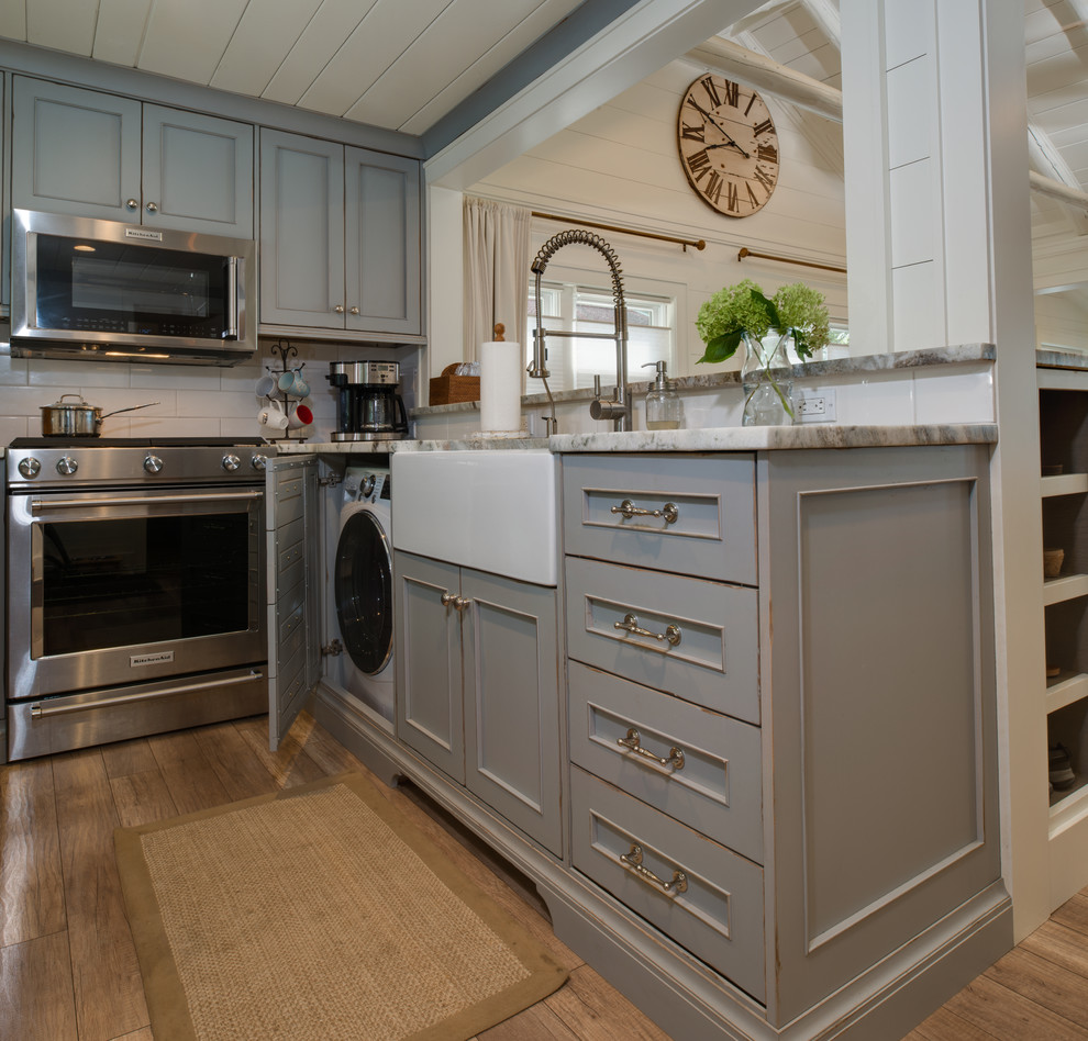 Small beach style u-shaped light wood floor and gray floor eat-in kitchen photo in Detroit with a farmhouse sink, beaded inset cabinets, gray cabinets, granite countertops, white backsplash, subway tile backsplash, stainless steel appliances, no island and gray countertops