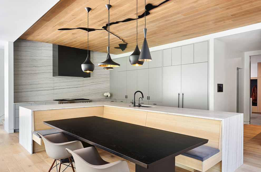 Immagine di una cucina design con lavello sottopiano, ante lisce, ante grigie, paraspruzzi bianco, elettrodomestici da incasso, parquet chiaro, pavimento marrone e top bianco