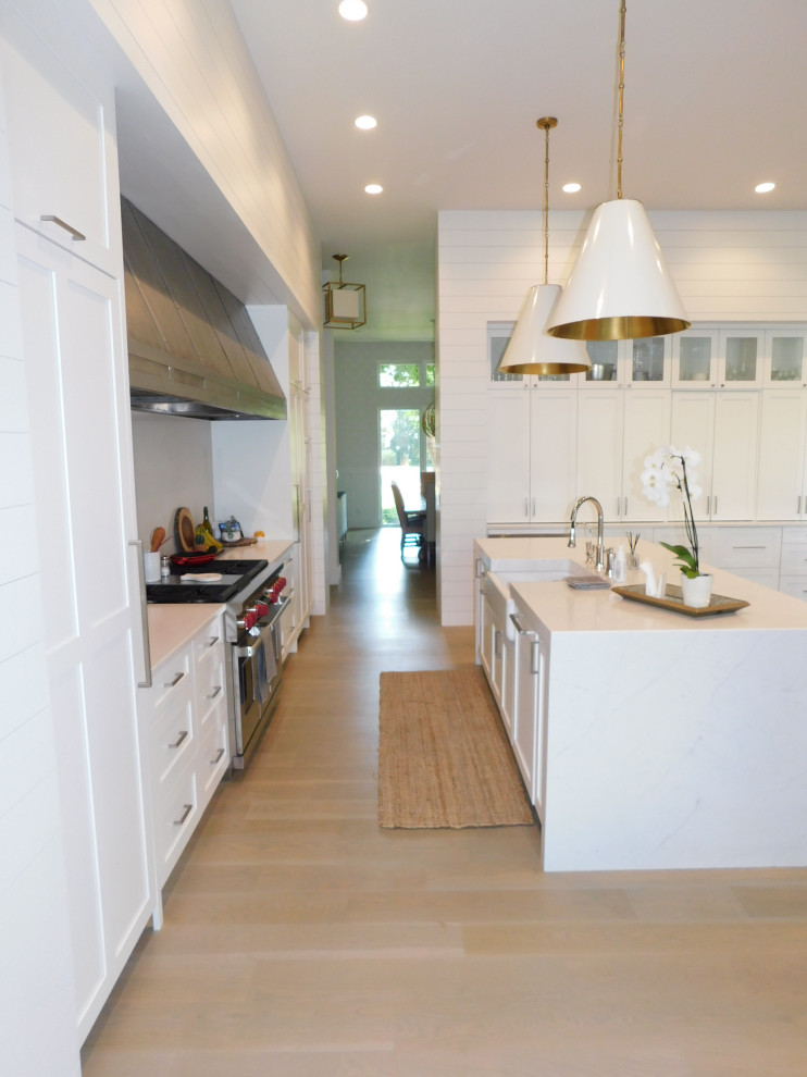 Inspiration for an expansive traditional l-shaped open plan kitchen in Denver with a belfast sink, flat-panel cabinets, white cabinets, marble worktops, white splashback, stone slab splashback, integrated appliances, medium hardwood flooring, an island, white floors, white worktops and a timber clad ceiling.