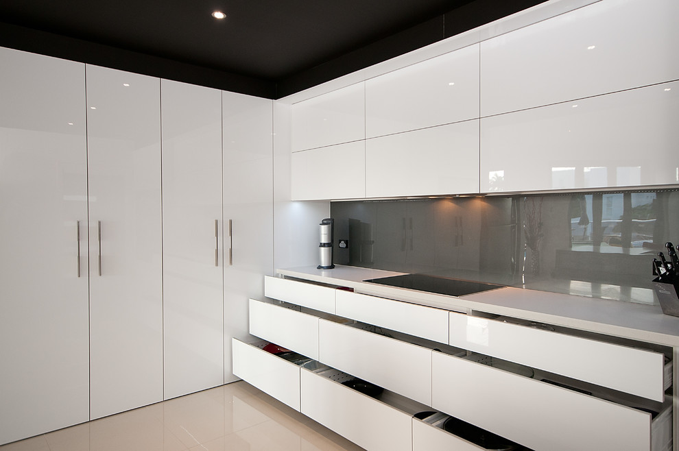 Example of a large minimalist single-wall ceramic tile enclosed kitchen design in Gold Coast - Tweed with an undermount sink, flat-panel cabinets, white cabinets, quartz countertops, gray backsplash, glass sheet backsplash, stainless steel appliances and an island