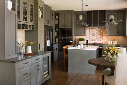 Kitchen and Bathroom Cabinets: gray shaker kitchen with glass-front uppers, built-in wine rack, large island, stainless appliances, and patterned tile backsplash.