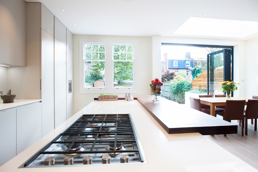 Exempel på ett mellanstort modernt linjärt kök med öppen planlösning, med en nedsänkt diskho, vita skåp, träbänkskiva, rostfria vitvaror, klinkergolv i porslin och en köksö