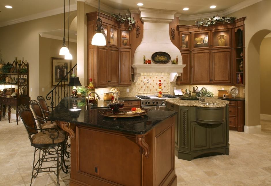 Example of a large tuscan l-shaped travertine floor kitchen pantry design in Orlando with an undermount sink, raised-panel cabinets, medium tone wood cabinets, granite countertops, beige backsplash, stone tile backsplash, stainless steel appliances and an island