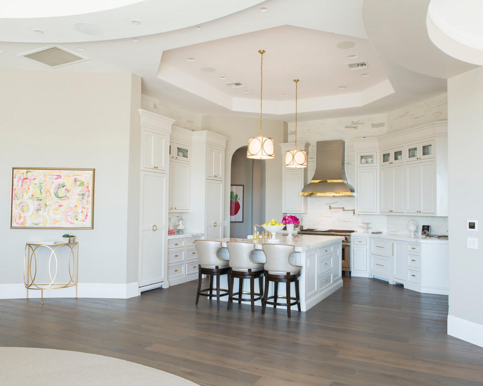 Example of a mid-sized transitional u-shaped dark wood floor and brown floor open concept kitchen design in Phoenix with a farmhouse sink, beaded inset cabinets, white cabinets, marble countertops, white backsplash, stainless steel appliances, an island and stone slab backsplash