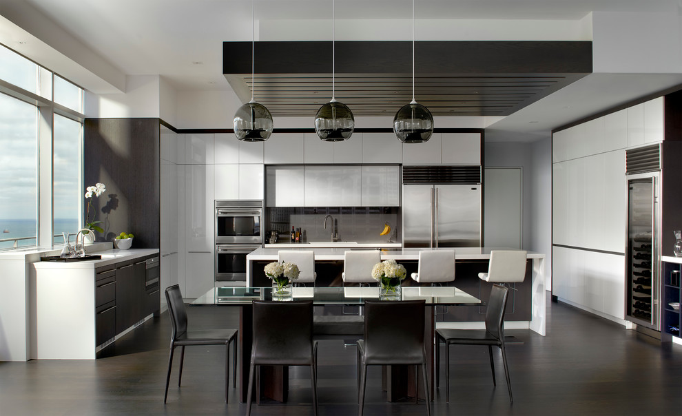Moderne Wohnküche in L-Form mit flächenbündigen Schrankfronten, weißen Schränken, Küchenrückwand in Grau, Glasrückwand und Küchengeräten aus Edelstahl in Chicago