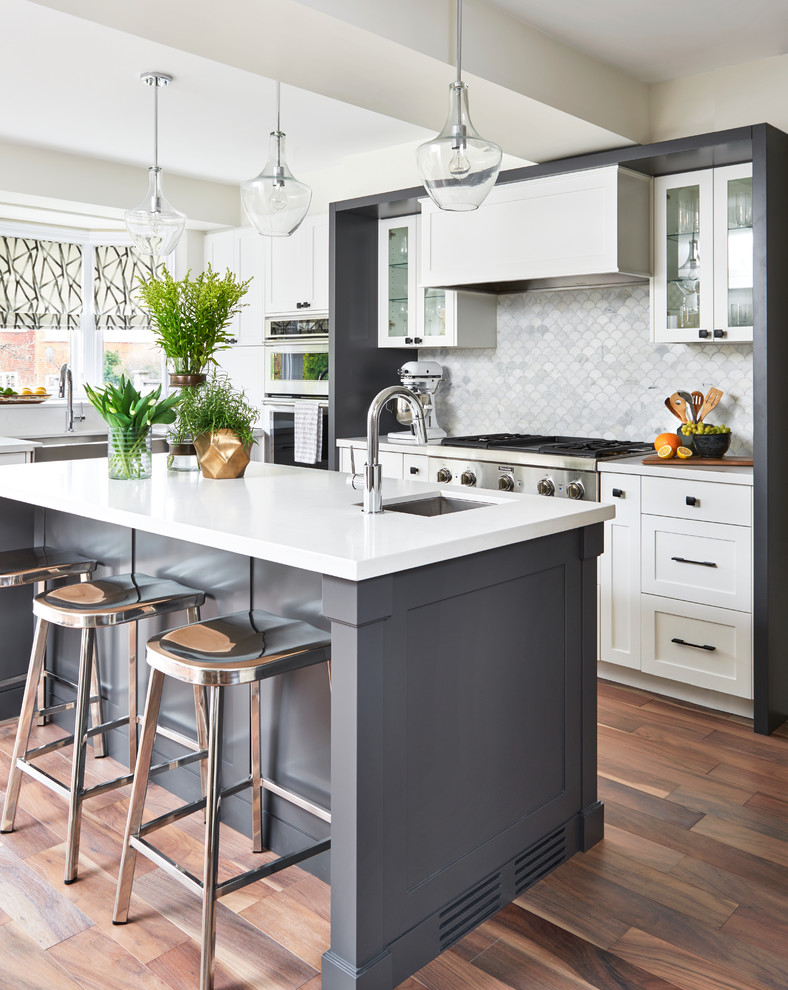 Inspiration for a contemporary l-shaped kitchen in Toronto with a belfast sink, shaker cabinets, white cabinets, white splashback, stainless steel appliances, dark hardwood flooring, an island and brown floors.