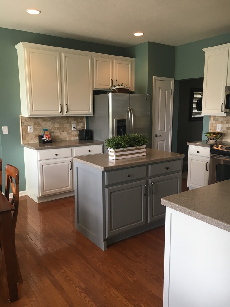 Medium sized traditional u-shaped kitchen/diner in Indianapolis with shaker cabinets, white cabinets, composite countertops, brown splashback, travertine splashback, stainless steel appliances, medium hardwood flooring, an island, brown floors, beige worktops and an integrated sink.