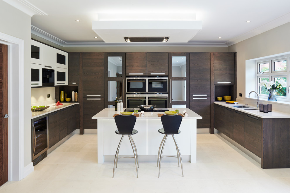 Свежая идея для дизайна: п-образная кухня-гостиная в современном стиле с плоскими фасадами, техникой под мебельный фасад, полом из керамической плитки, полуостровом, врезной мойкой и темными деревянными фасадами - отличное фото интерьера
