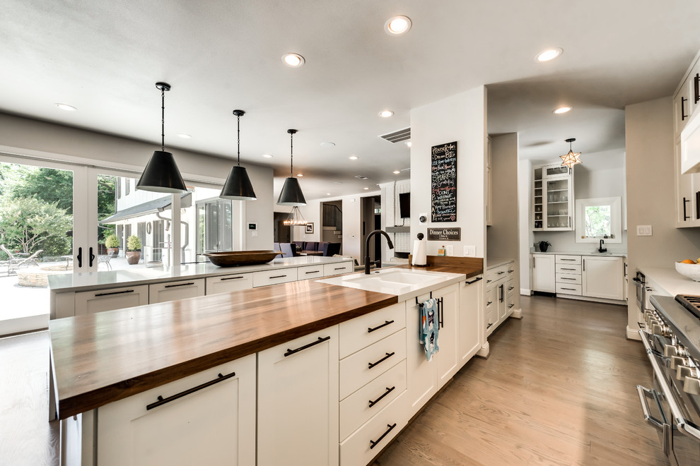 Inspiration for a transitional single-wall light wood floor and brown floor eat-in kitchen remodel in Dallas with a double-bowl sink, shaker cabinets, white cabinets, wood countertops, green backsplash, stainless steel appliances, two islands and ceramic backsplash