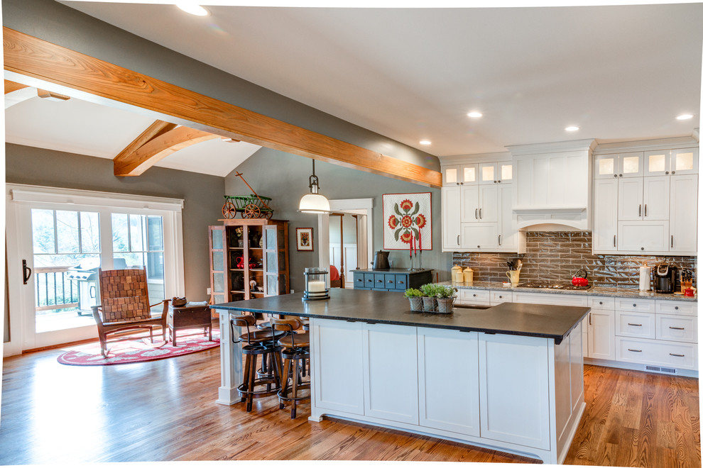 Foto på ett mellanstort vintage grå kök, med en rustik diskho, skåp i shakerstil, vita skåp, bänkskiva i täljsten, grått stänkskydd, stänkskydd i tunnelbanekakel, rostfria vitvaror, mellanmörkt trägolv, en köksö och brunt golv