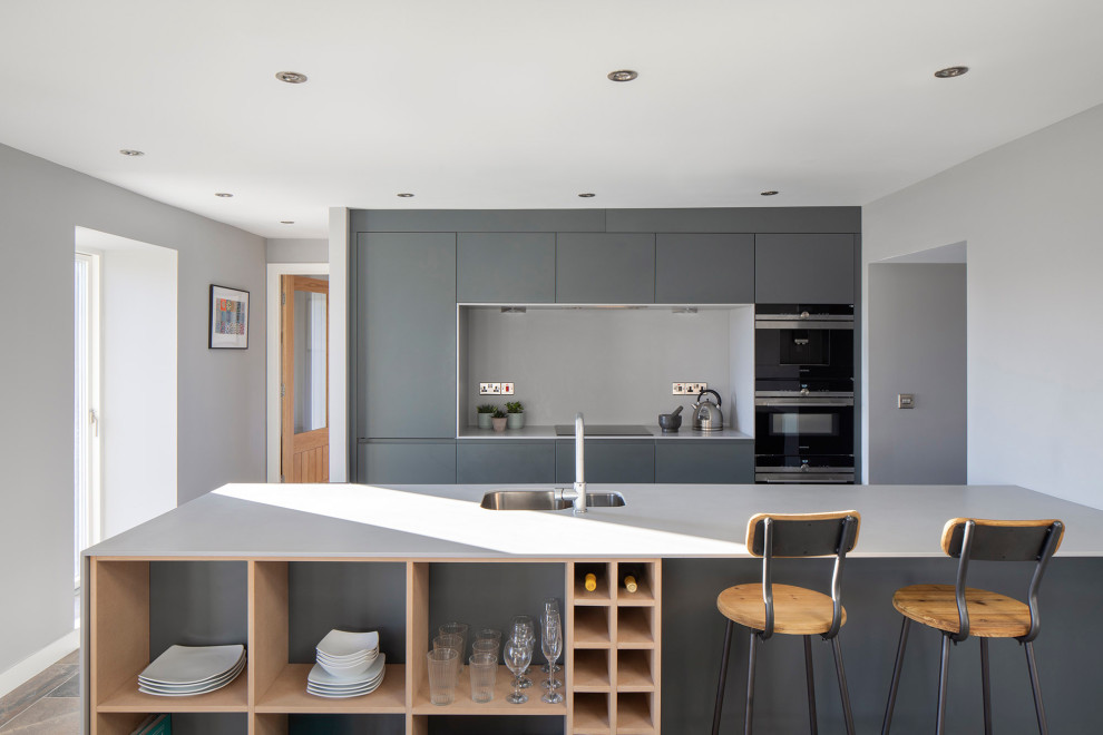 Foto di una cucina contemporanea con lavello sottopiano, ante lisce, ante grigie, paraspruzzi grigio, elettrodomestici in acciaio inossidabile, pavimento marrone e top bianco