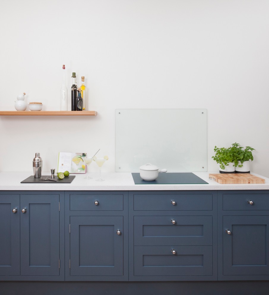 Immagine di una piccola cucina lineare chic chiusa con lavello da incasso, ante in stile shaker, ante blu, top in superficie solida, paraspruzzi con lastra di vetro, elettrodomestici neri, parquet chiaro e nessuna isola