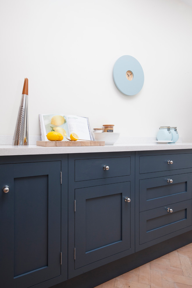 Esempio di una piccola cucina lineare classica chiusa con lavello da incasso, ante in stile shaker, ante blu, top in superficie solida, paraspruzzi con lastra di vetro, elettrodomestici neri, parquet chiaro e nessuna isola