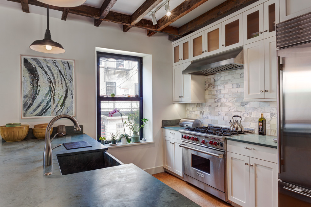 Example of a mid-sized cottage single-wall cork floor kitchen design in New York with a farmhouse sink, shaker cabinets, white cabinets, limestone countertops, white backsplash, stone tile backsplash, stainless steel appliances and a peninsula