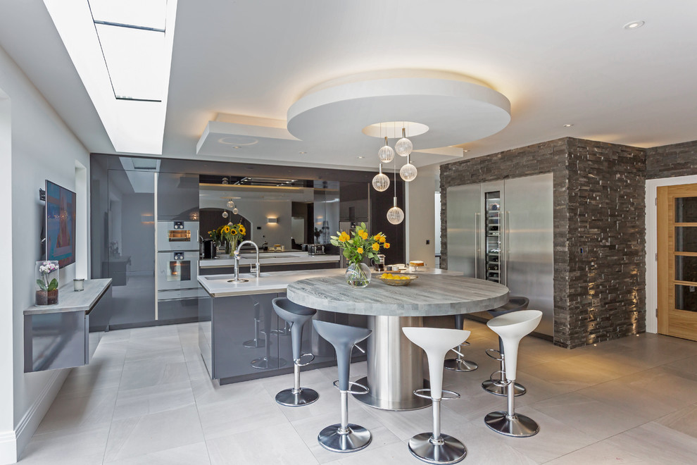 Inspiration for a large contemporary kitchen/diner in Manchester with a built-in sink, grey cabinets, granite worktops, metallic splashback, glass sheet splashback, stainless steel appliances, porcelain flooring, multiple islands, grey floors and white worktops.