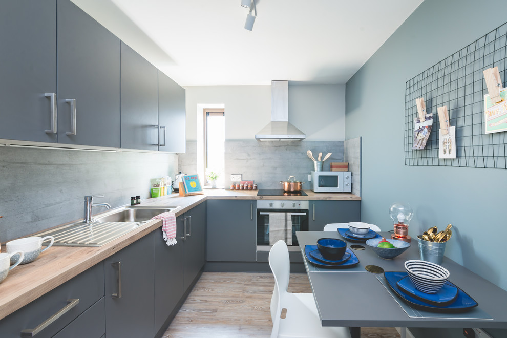 This is an example of a contemporary l-shaped kitchen/diner in Other with a built-in sink, flat-panel cabinets, grey cabinets, grey splashback, brown floors and brown worktops.