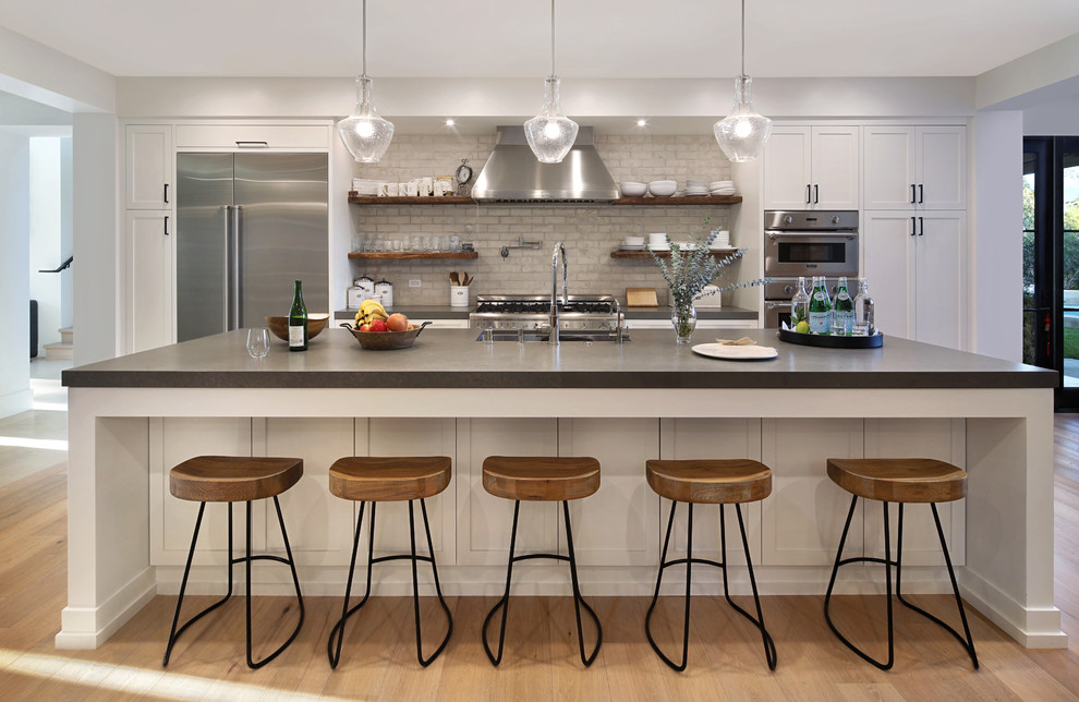 Inspiration for a contemporary galley kitchen in Orange County with a submerged sink, shaker cabinets, white cabinets, grey splashback, stainless steel appliances, medium hardwood flooring, an island, brown floors and grey worktops.