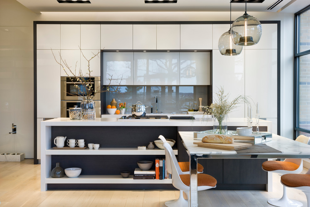 Design ideas for a contemporary single-wall kitchen/diner in DC Metro with flat-panel cabinets, white cabinets, light hardwood flooring, an island, grey splashback, a submerged sink, glass sheet splashback and integrated appliances.