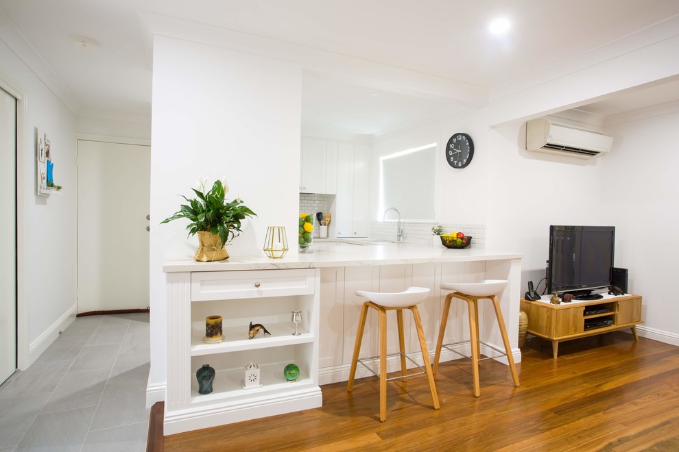Small elegant u-shaped porcelain tile and gray floor kitchen pantry photo in Brisbane with a double-bowl sink, shaker cabinets, white cabinets, quartz countertops, gray backsplash, ceramic backsplash, black appliances, an island and white countertops