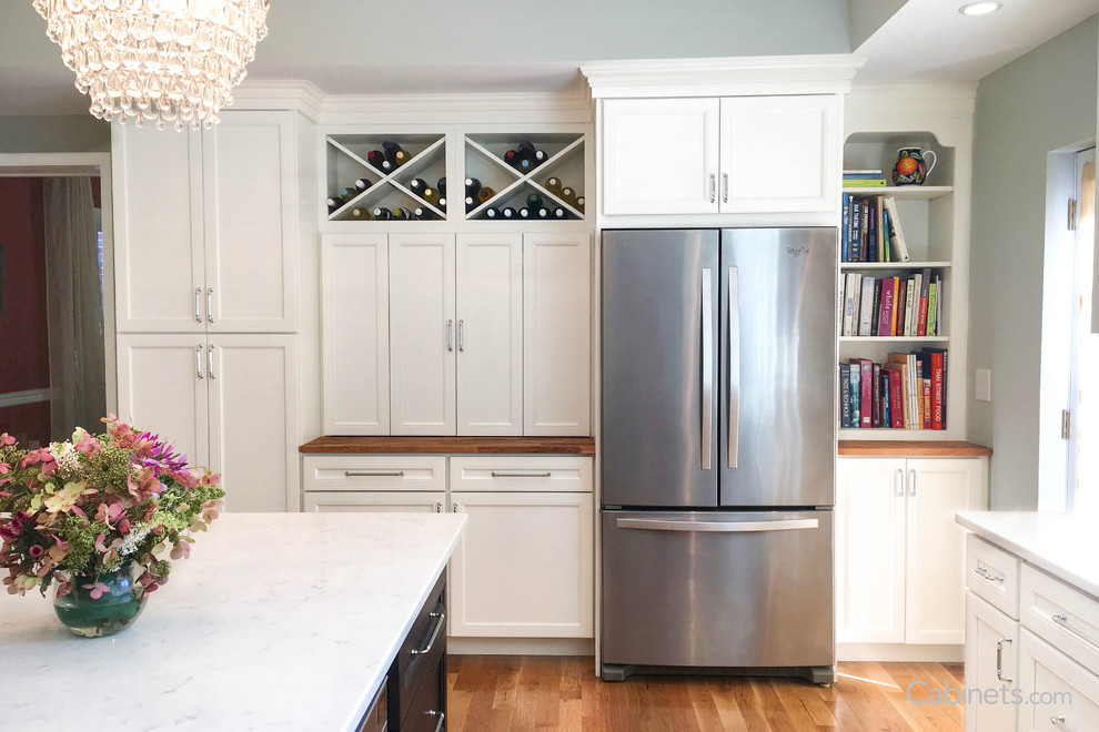 Imagen de cocina clásica renovada de tamaño medio con armarios con paneles empotrados, puertas de armario blancas, una isla y suelo beige
