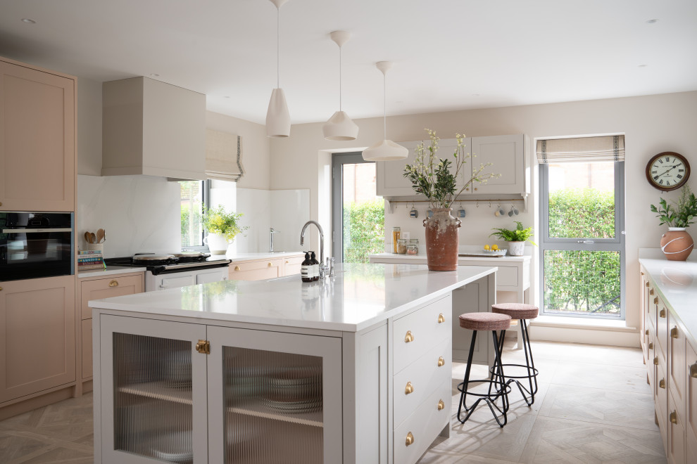 Example of a large danish u-shaped porcelain tile open concept kitchen design in Belfast with a farmhouse sink, shaker cabinets, solid surface countertops, an island and white countertops