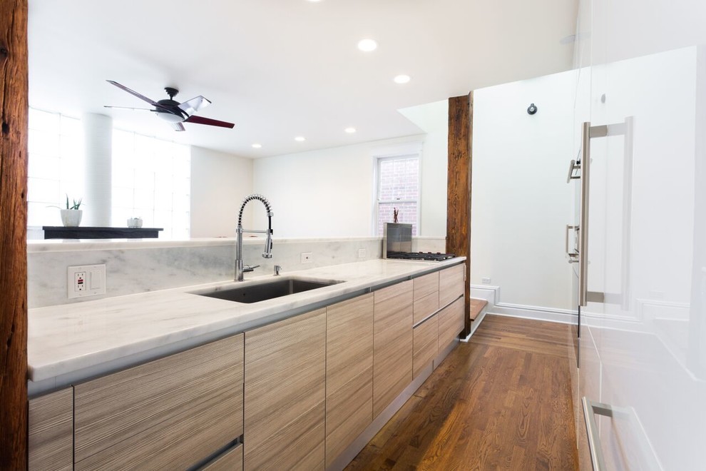 Example of a large trendy single-wall medium tone wood floor eat-in kitchen design in Chicago with an undermount sink, flat-panel cabinets, white cabinets, marble countertops, paneled appliances and an island