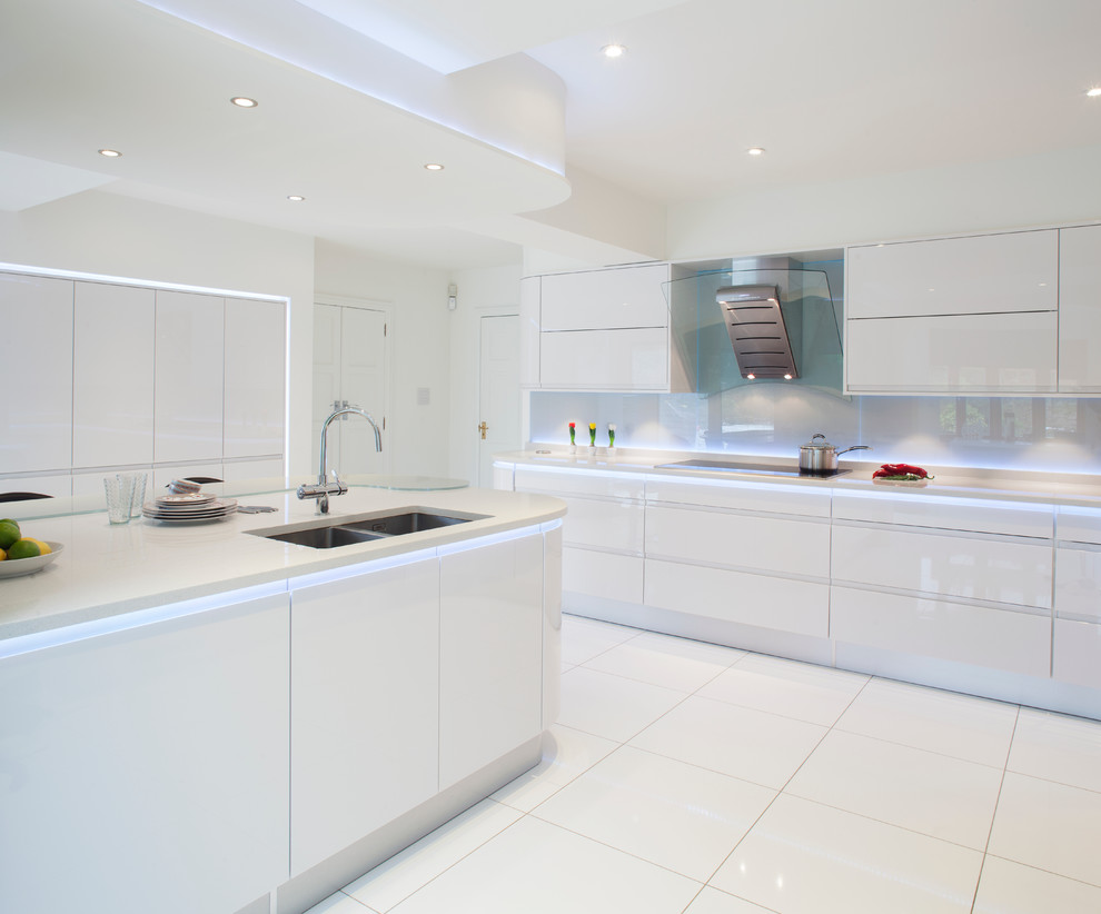 Medium sized contemporary u-shaped kitchen/diner in Other with a double-bowl sink, flat-panel cabinets, white cabinets, recycled glass countertops, white splashback, glass sheet splashback, ceramic flooring, an island and white floors.