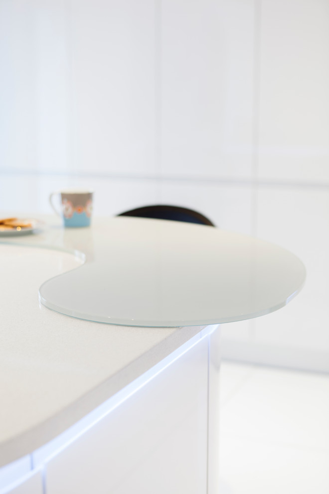 Inspiration for a medium sized contemporary u-shaped kitchen/diner in Other with a double-bowl sink, flat-panel cabinets, white cabinets, recycled glass countertops, white splashback, glass sheet splashback, ceramic flooring, an island and white floors.