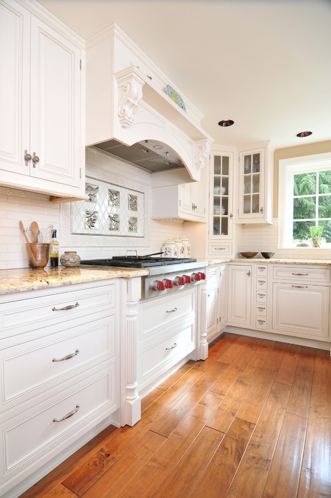 Inspiration for a timeless u-shaped eat-in kitchen remodel in Seattle with an undermount sink, white cabinets, granite countertops, white backsplash, ceramic backsplash and paneled appliances