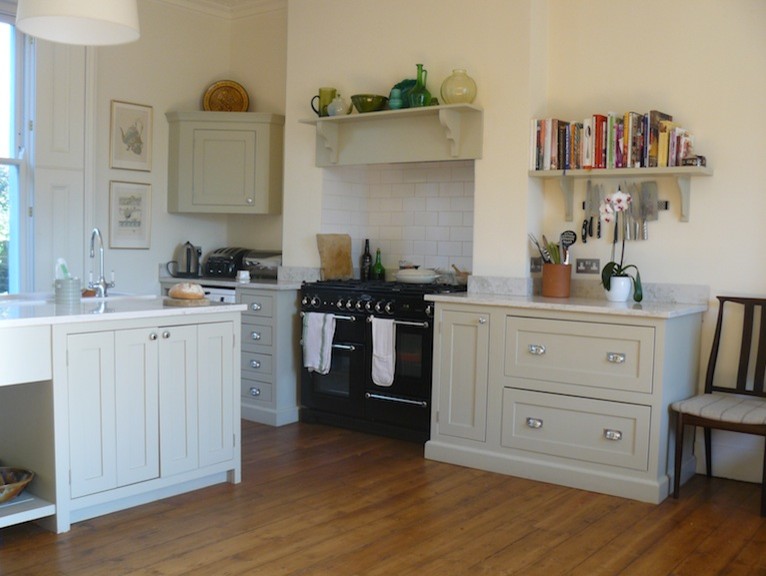 This is an example of a medium sized traditional u-shaped open plan kitchen in Surrey with beaded cabinets, beige cabinets, an island and white worktops.
