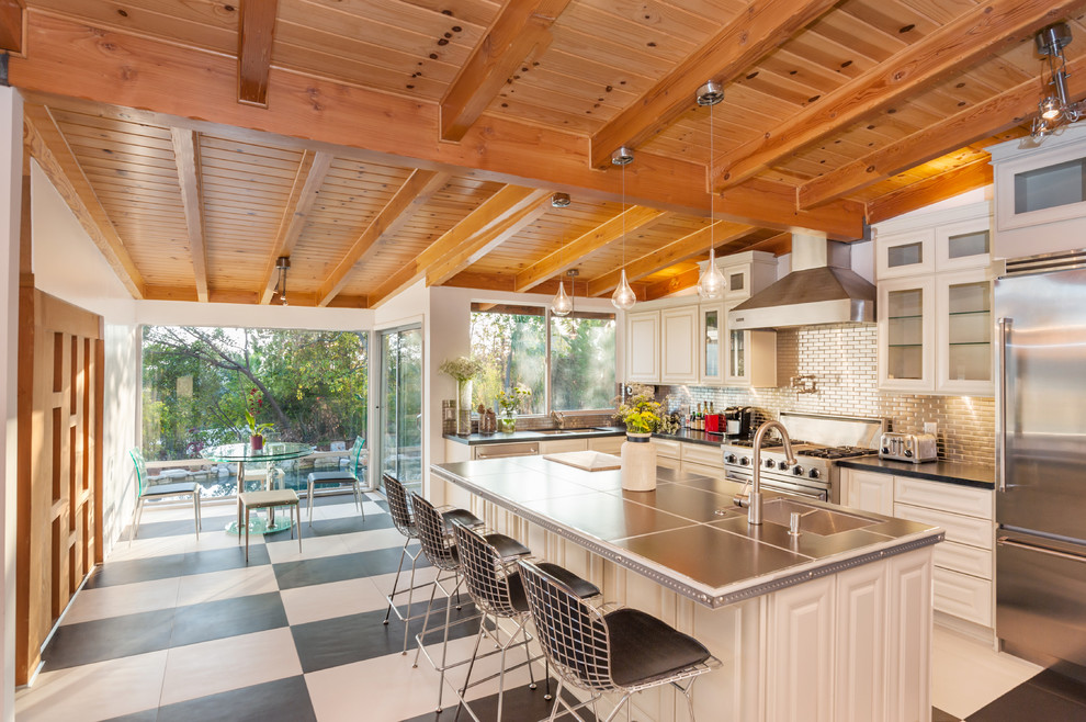 Inspiration for a large transitional l-shaped eat-in kitchen remodel in Los Angeles with an undermount sink, raised-panel cabinets, white cabinets, metallic backsplash, metal backsplash, stainless steel appliances and an island