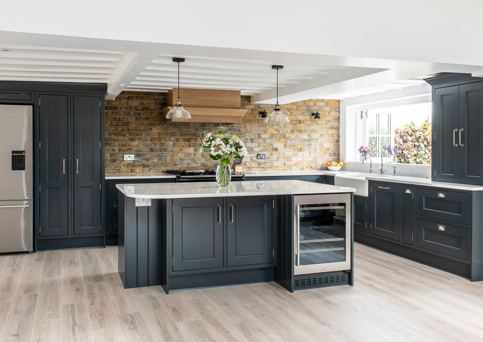 Klassische Küche mit dunklen Holzschränken, Rückwand aus Backstein und Kücheninsel in Kent