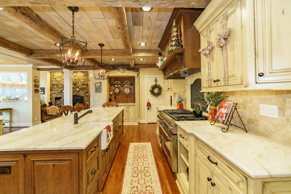 Foto på ett stort rustikt beige kök, med en rustik diskho, luckor med profilerade fronter, gula skåp, bänkskiva i kvartsit, beige stänkskydd, stänkskydd i marmor, rostfria vitvaror, mellanmörkt trägolv och flera köksöar