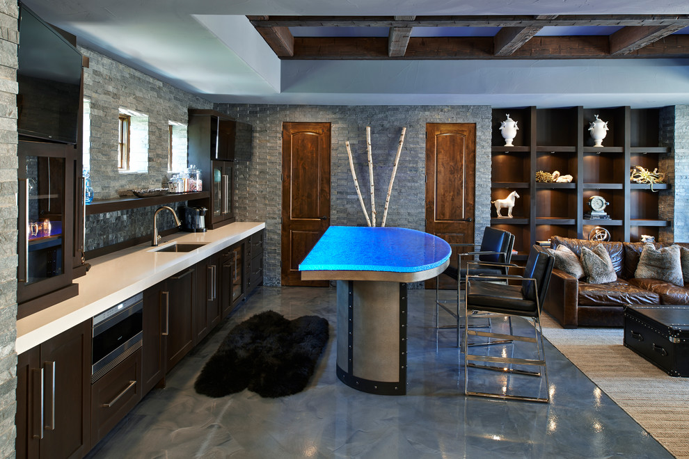 Idées déco pour une cuisine ouverte linéaire industrielle en bois foncé avec un plan de travail bleu, un évier encastré, un placard à porte shaker, un plan de travail en verre, îlot, un sol gris et fenêtre au-dessus de l'évier.