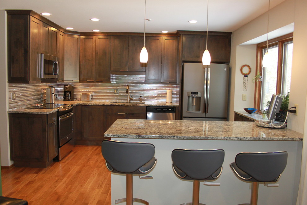 Example of a small transitional l-shaped medium tone wood floor eat-in kitchen design in Chicago with an undermount sink, shaker cabinets, dark wood cabinets, granite countertops, gray backsplash, metal backsplash, stainless steel appliances and a peninsula