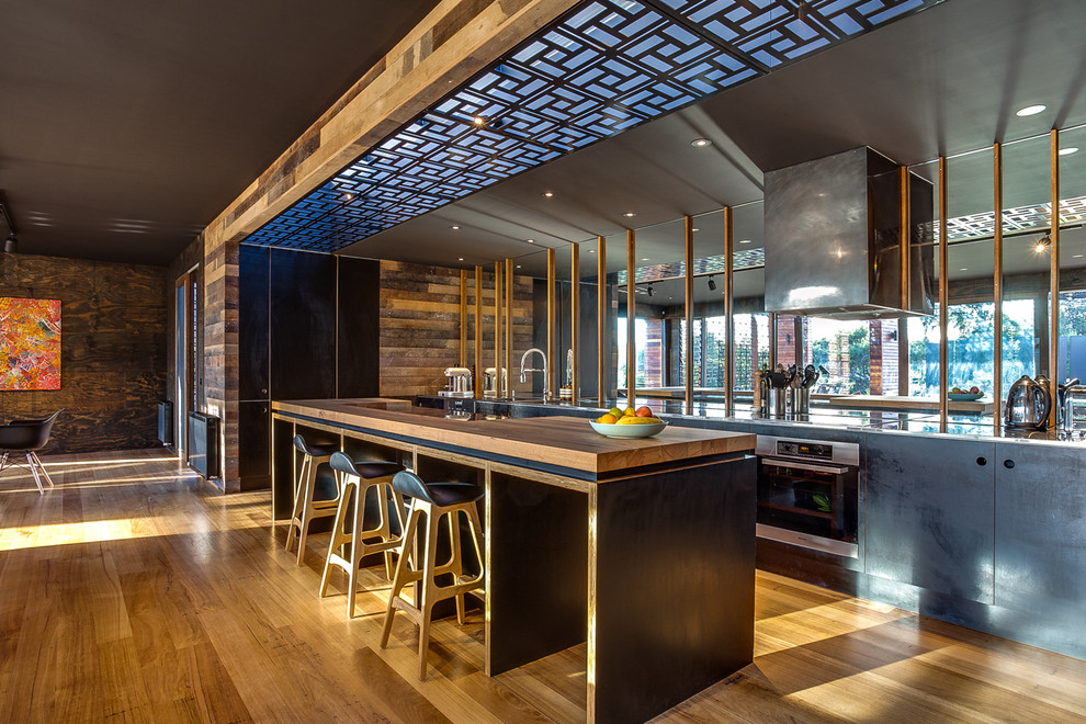 Immagine di una grande cucina contemporanea con ante lisce, ante nere, top in legno, paraspruzzi a effetto metallico, paraspruzzi a specchio e pavimento in legno massello medio