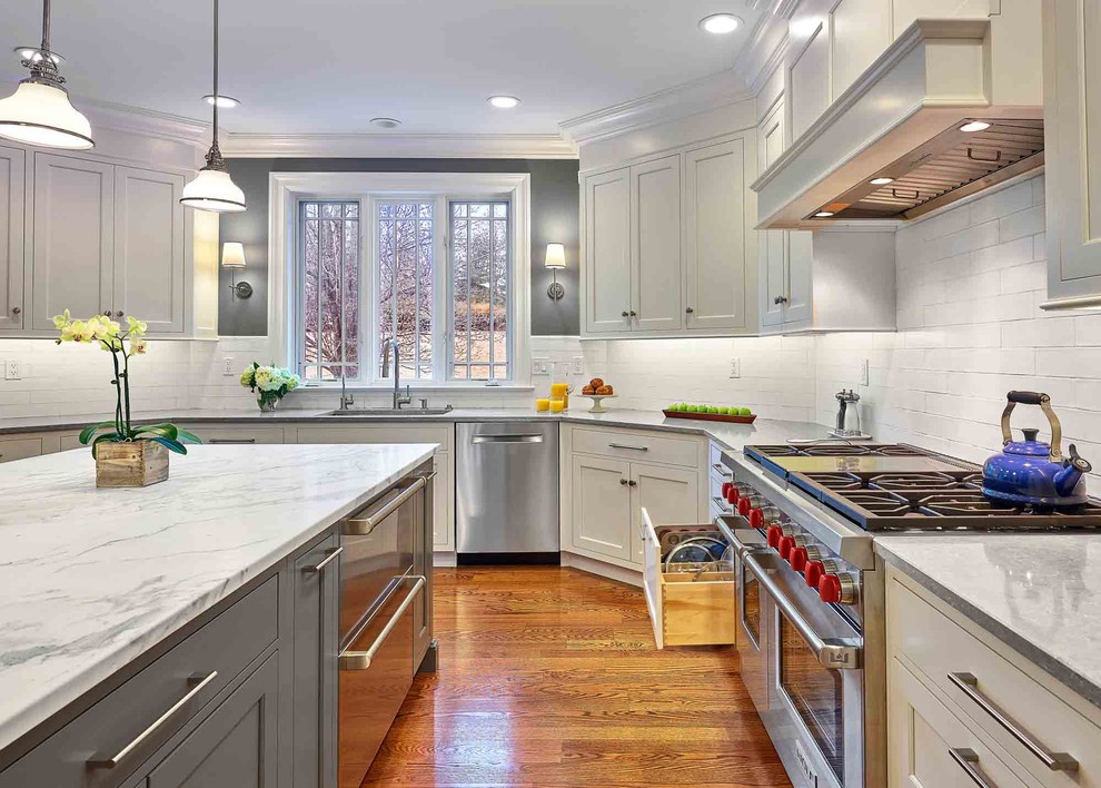 Exempel på ett stort klassiskt grå grått kök, med en nedsänkt diskho, luckor med profilerade fronter, vita skåp, bänkskiva i kalksten, vitt stänkskydd, stänkskydd i keramik, rostfria vitvaror, mellanmörkt trägolv, en köksö och brunt golv