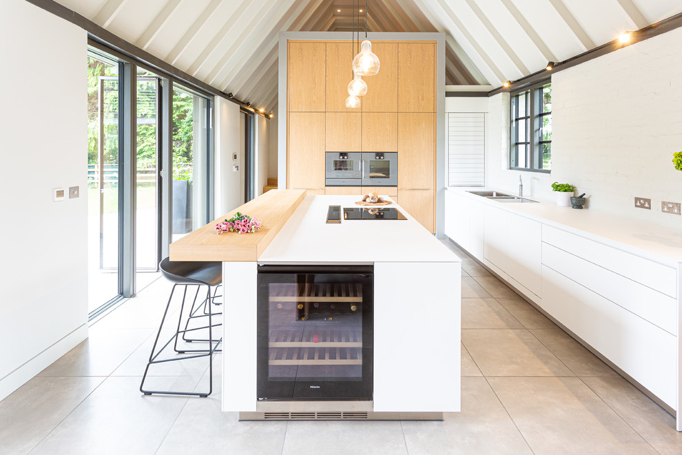 Inspiration for a contemporary kitchen in Wiltshire with a double-bowl sink, flat-panel cabinets, white cabinets, white splashback, an island, beige floors and white worktops.