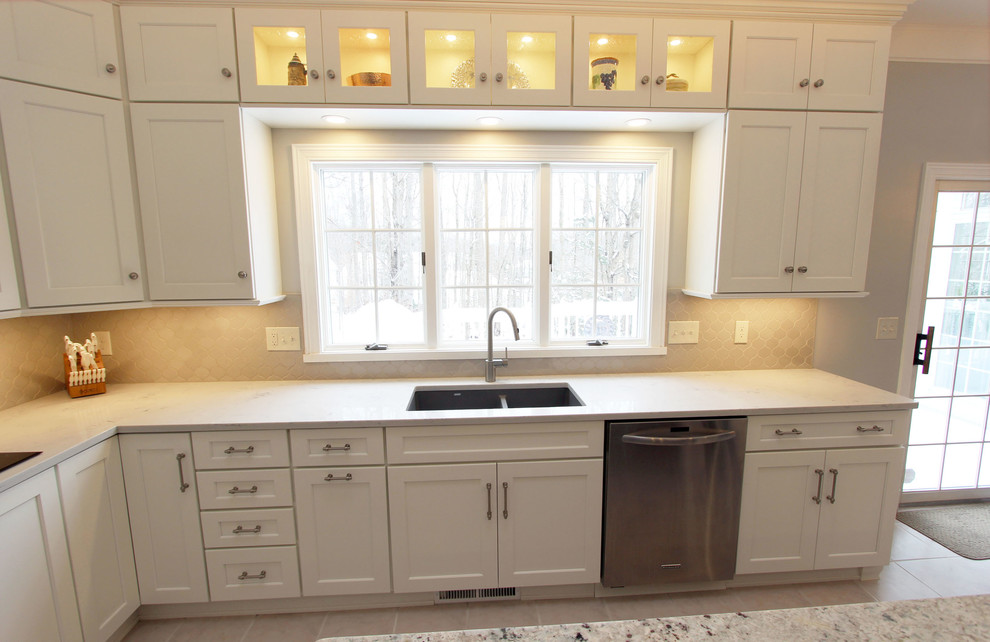 Exempel på ett stort klassiskt beige beige kök, med en undermonterad diskho, släta luckor, vita skåp, bänkskiva i kvarts, beige stänkskydd, stänkskydd i glaskakel, rostfria vitvaror och en köksö