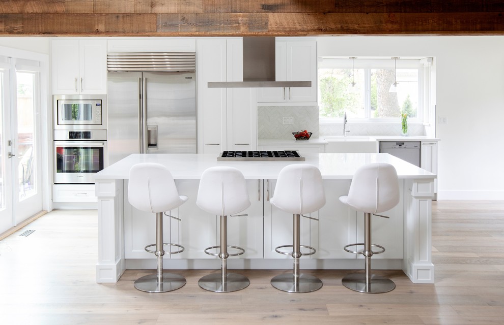 Foto di una grande cucina contemporanea con lavello stile country, ante in stile shaker, ante bianche, paraspruzzi grigio, elettrodomestici in acciaio inossidabile, parquet chiaro, pavimento beige, top in quarzo composito, paraspruzzi in marmo e top bianco