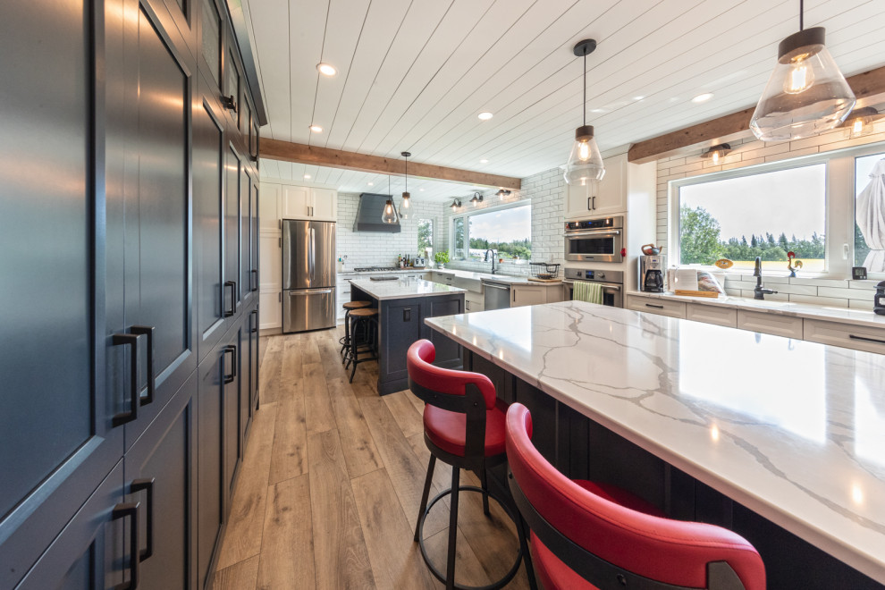 Eat-in kitchen - large craftsman l-shaped vinyl floor, brown floor and shiplap ceiling eat-in kitchen idea in Edmonton with a farmhouse sink, shaker cabinets, blue cabinets, granite countertops, white backsplash, porcelain backsplash, stainless steel appliances, two islands and white countertops