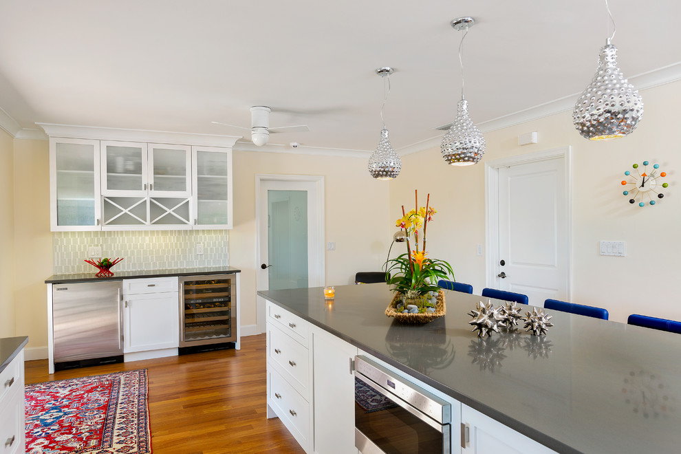 Moderne Küche in L-Form mit Schrankfronten im Shaker-Stil, weißen Schränken, Quarzwerkstein-Arbeitsplatte, Rückwand aus Glasfliesen, braunem Holzboden und Kücheninsel in Miami