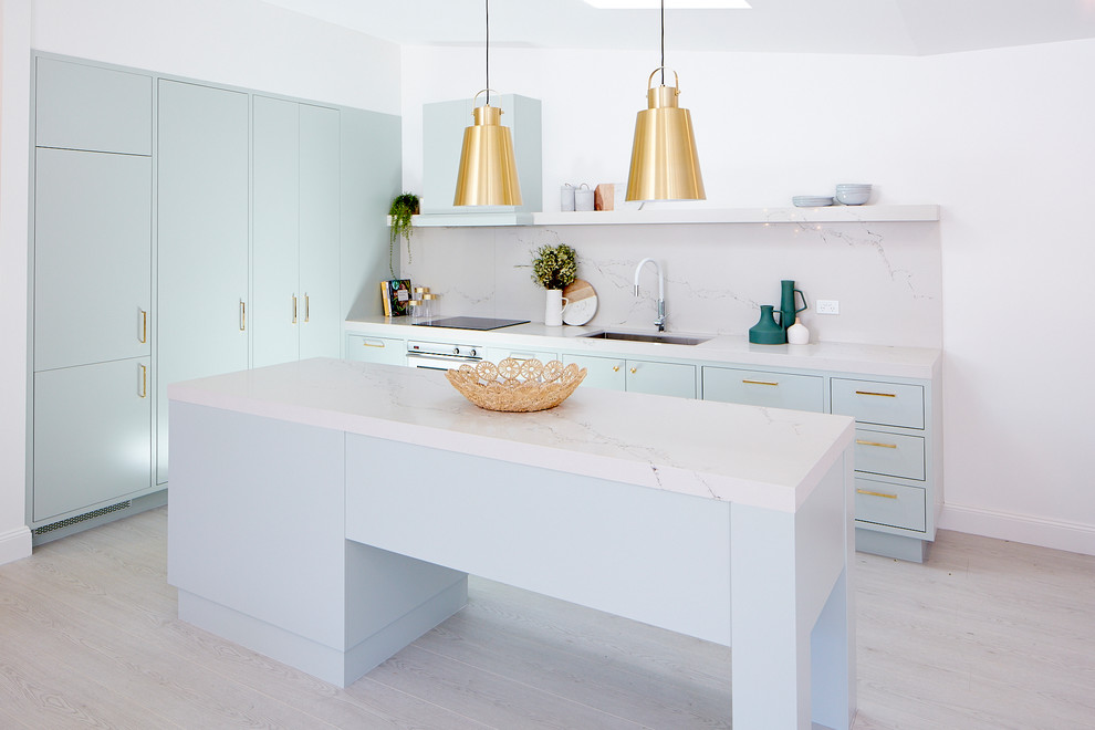 Idee per una piccola cucina moderna con lavello sottopiano, ante lisce, ante blu, top in marmo, paraspruzzi bianco, paraspruzzi in marmo, elettrodomestici da incasso, parquet chiaro e pavimento bianco