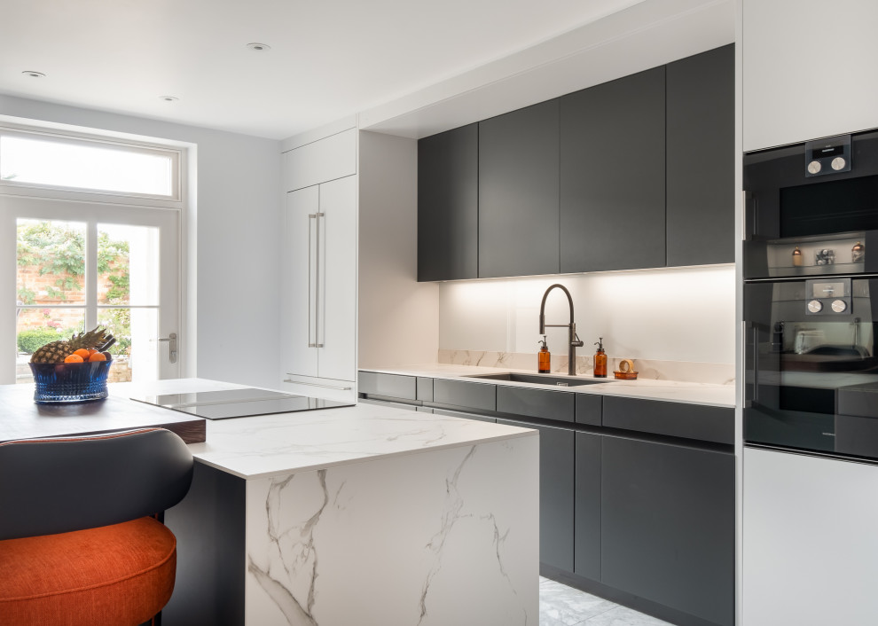Mittelgroße Moderne Wohnküche mit flächenbündigen Schrankfronten, grauen Schränken, Mineralwerkstoff-Arbeitsplatte, schwarzen Elektrogeräten, Marmorboden, Kücheninsel und weißer Arbeitsplatte in Gloucestershire