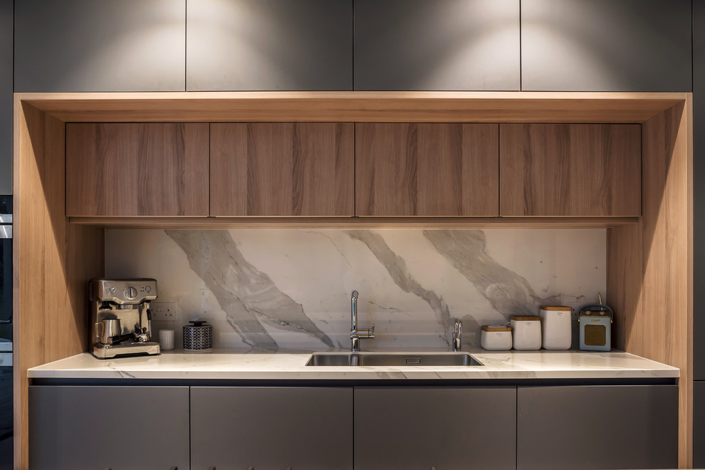 Immagine di una cucina contemporanea con ante lisce, ante grigie, paraspruzzi bianco, parquet chiaro, pavimento beige e top bianco