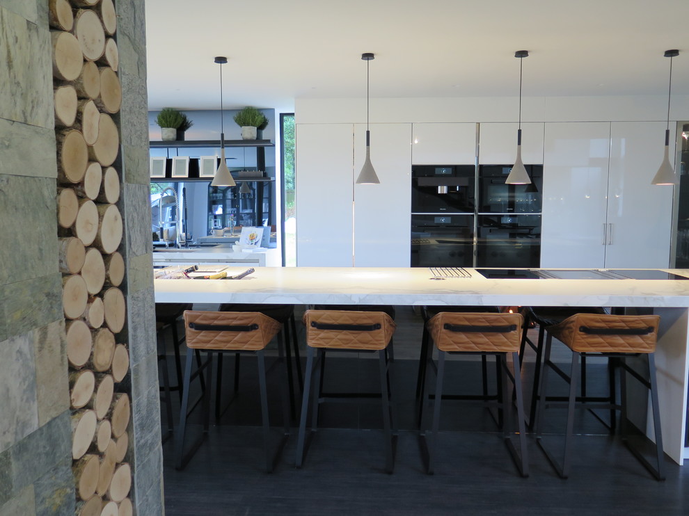 Bild på ett stort funkis linjärt kök, med en integrerad diskho, släta luckor, vita skåp, marmorbänkskiva, spegel som stänkskydd, rostfria vitvaror, klinkergolv i keramik och en köksö