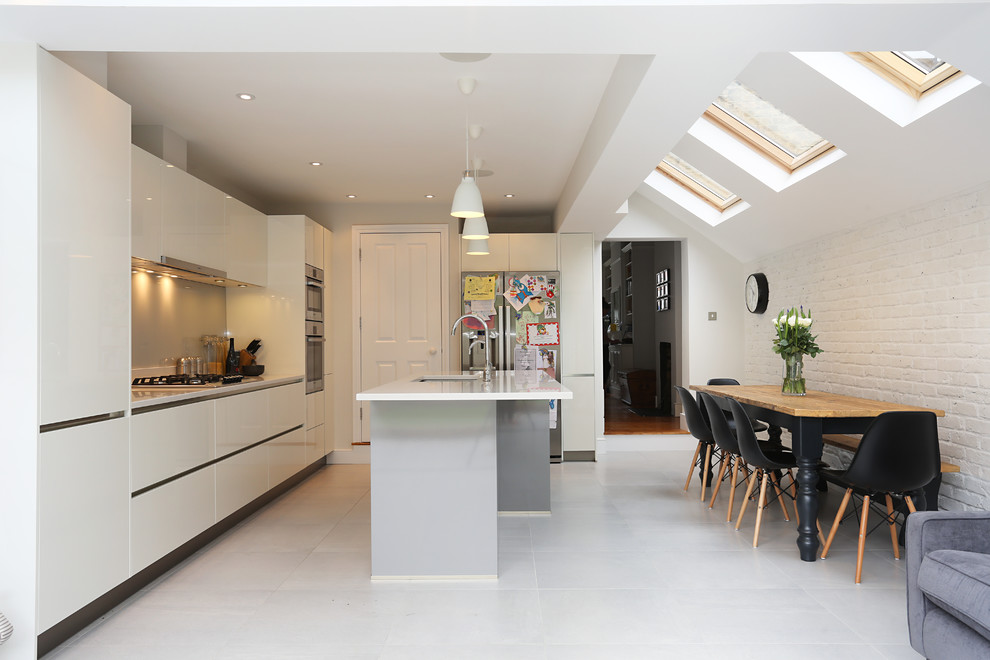 Zweizeilige Moderne Wohnküche mit flächenbündigen Schrankfronten, weißen Schränken und Kücheninsel in London