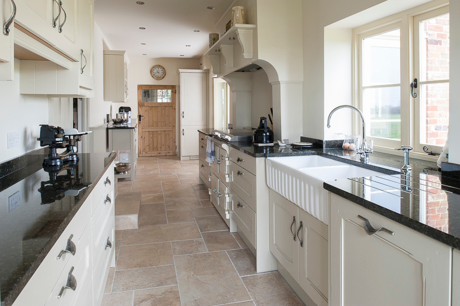 Zweizeilige, Kleine Klassische Küche mit Einbauwaschbecken, weißen Schränken, Granit-Arbeitsplatte, Elektrogeräten mit Frontblende und Porzellan-Bodenfliesen in Kent
