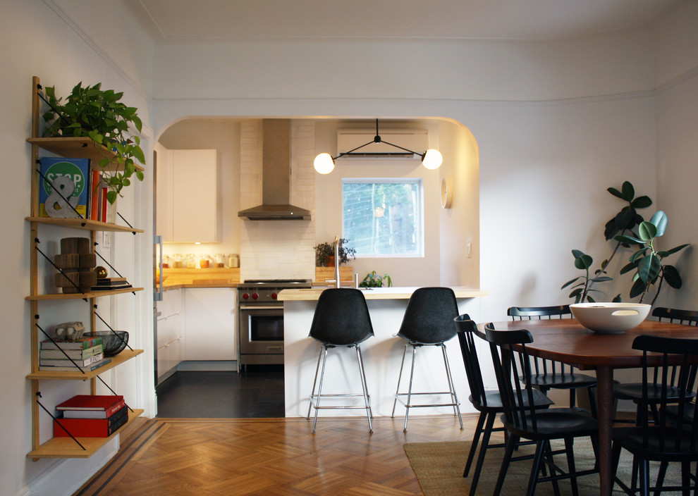 Immagine di una cucina moderna di medie dimensioni con lavello sottopiano, ante lisce, ante bianche, top in legno, elettrodomestici in acciaio inossidabile e pavimento in vinile