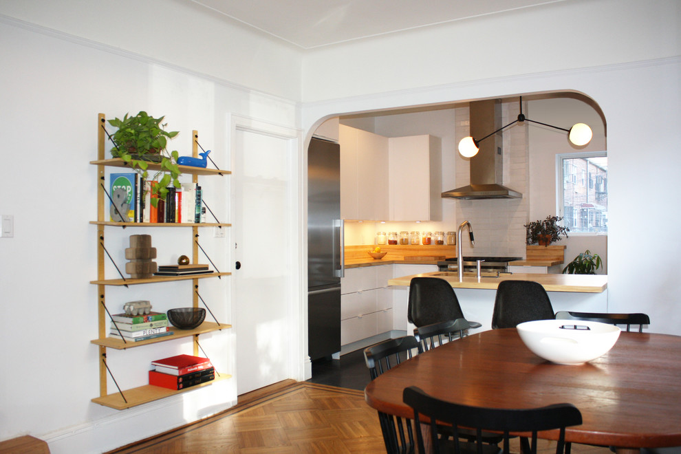 Idéer för att renovera ett mellanstort funkis kök, med en undermonterad diskho, släta luckor, vita skåp, träbänkskiva, rostfria vitvaror, vinylgolv och en köksö